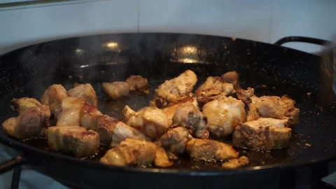 Close-up of man stirring chicken and pork meat in a paella Stock Footage 147988754