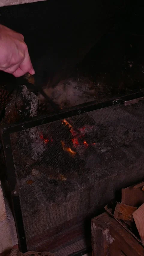 Close-up: man stoking the fire with a fireplace poker. Man tending the hearth 動画素材 340486344
