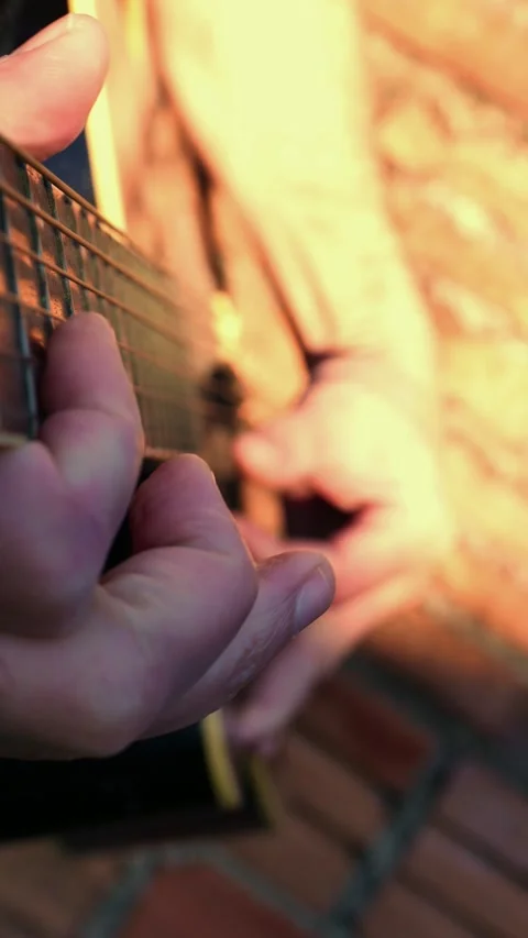 Close-up: man strumming a guitar under the afternoon sunlight. POV: Guitar neck Stock Footage 334910824