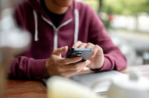 Close up of a man student freelancer typing or looking at phone while sits .. Stock Photos