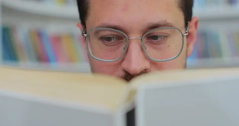 Close up man student in glasses is spending his time in library, examining a Stock Footage 208816591