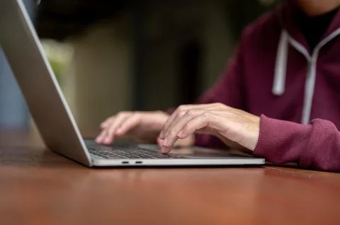 Close up of a man student or freelancer typing both hands on laptop sitting.. Stock Photos