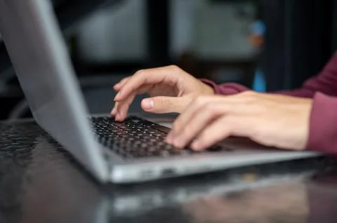Close up of a man student's hand typing on laptop's keyboard on shiny black.. Stock Photos
