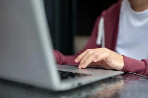Close up of a man student's hand typing or tapping on laptop at shiny black.. Stock Photos