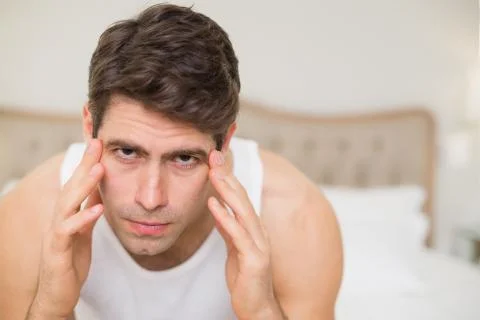 Close up of man suffering from headache in bed Stock Photos