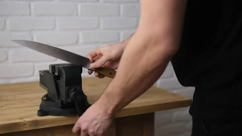 Close-up of a man taking a knife from a black vise with a screw handle and a cas Stock Footage 146950206
