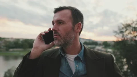 Close up, man talking on mobile phone while standing on the embankment of the Stockbeeldmateriaal 221532182