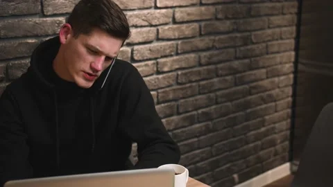 Close up man talking on phone, man using on laptop, discussing new startup Stock Footage 148384378