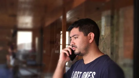 Close-up of a man talking on the phone outside the house because his friends are Stock Footage 199477688