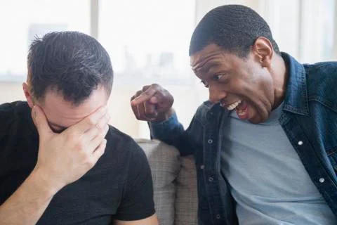 Close up of man teasing friend on sofa Stock Photos