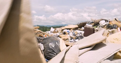 Close up of a man throwing old carpeting in a landfill Stock Footage 89361687