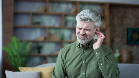 Close-up of man touching his ear and wincing from sharp pain at home.  Stock Footage 328706100