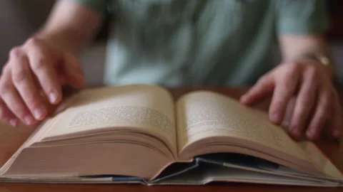 Close up on a man turning the pages of an old book while sitting at a desk Stock Footage 134291285