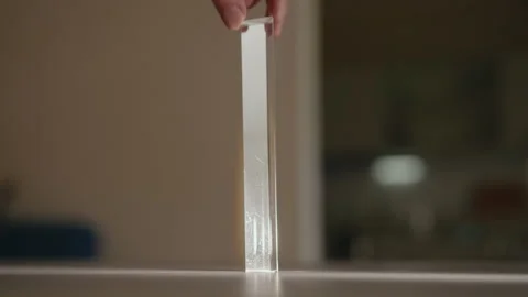 Close-up of man twirling triangular glass prism, light passes through creating Stock Footage 312352750