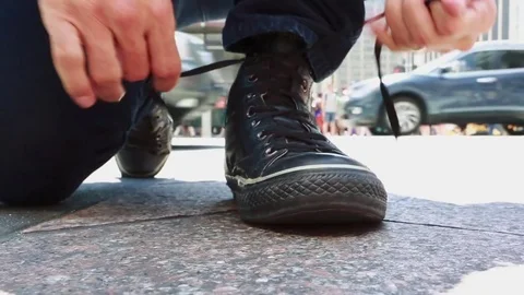 Close-up of man tying his shoes in a busy street Stock Footage
