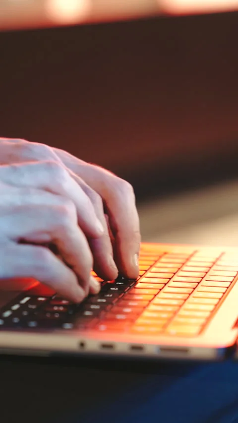 Close up Man typing on a modern laptop, streetlights at night. The background is Stock Footage 323580727