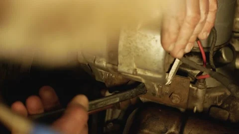 Close up man unscrews nut of the generator in old car with v8 engine Video stock 131406297