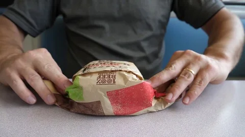 Close up man unwraps burger whooper sandwich inside Burger King restaurant Stock Footage 80618930