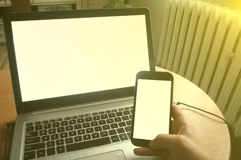 Close up of man using blank cell phone and laptop sending massages shopping o Stock-Fotos