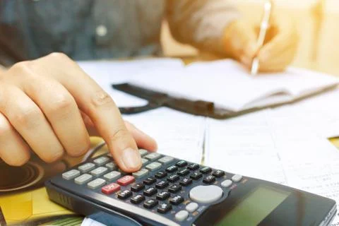 Close up man using calculator and writing make note in home office. Stock Photos