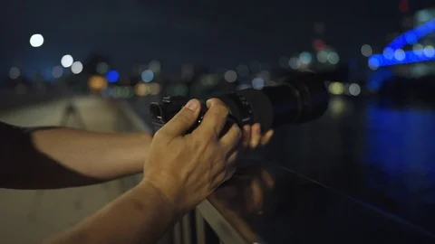 Close up of Man Using Camera at Night, taking a phot of a blue bridge. Stock Footage 122722071