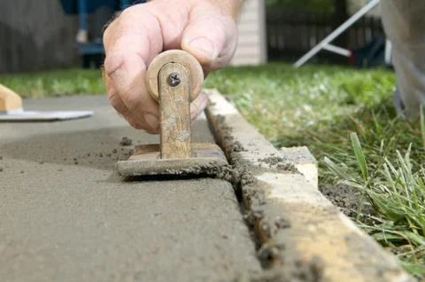 Close up of a man using edging tool on wet cement Stock Photos