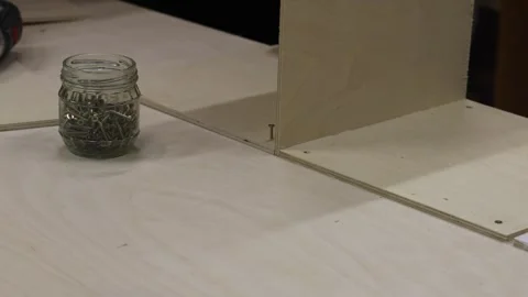 Close-up of man using electric screwdriver to assemble wooden furniture. DIY woo Stock Footage 327973479