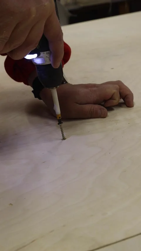 Close-up of man using electric screwdriver to drive screw into wooden board. DIY Stock Footage 327973696