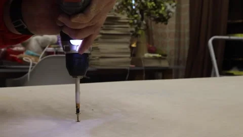 Close-up of man using electric screwdriver to drive screw into wooden board. DIY Stock Footage 327973707