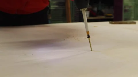 Close-up of man using electric screwdriver to drive screw into wooden board. DIY Stock Footage 327973778