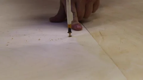 Close-up of man using electric screwdriver to drive screw into wooden board. DIY Stock Footage 327973784