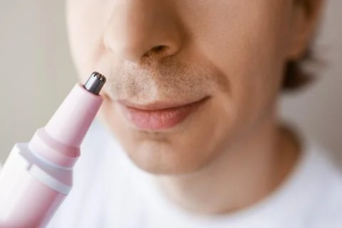 Close-up of a man using an electric trimmer for nose hair removal. Daily fa.. Stockfoto's