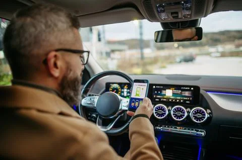 Close up of man using electric vehicle charging app, checking battery level on Stock Photos