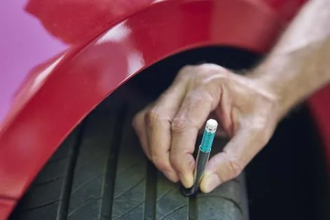 Close up of man using  gauge to check tyre tread depth on car 写真素材