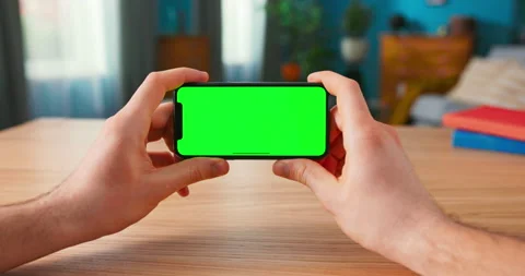 Close-up of Man Using Green Mock-up Screen Smartphone in Landscape Mode while Stock Footage 154854614