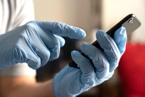 CLOSE UP of a man using his phone while wearing gloves during COVID-19. Stock Photos