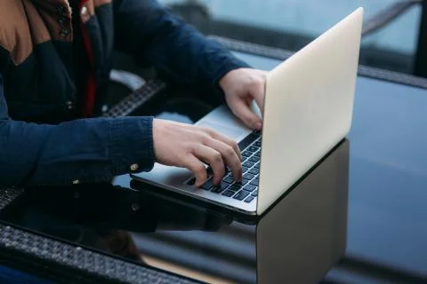 Close up of man using laptop on the table. Cappuchino on the glass table Stock-Fotos