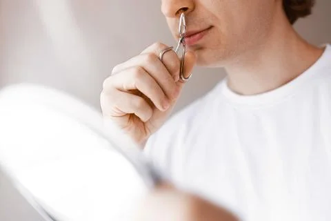 Close up of a man using a manual metal trimmer for nose hair removal. Male .. Stock Photos