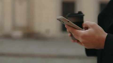Close up of man using mobile and carrying coffee outdoors Stock Footage 168475824