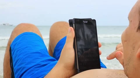 Close up of man using smart phone while laying down on a beach. Koh Samui. Vídeos de archivo 44015778