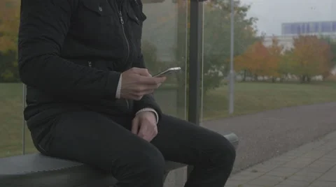 Close-up of a man using smart phone at a bus stop Stock Footage 68679238