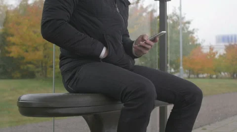 Close-up of a man using smart phone at a bus stop Stock Footage 68679273