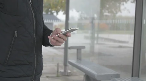 Close-up of a man using smart phone at a bus stop Stock Footage 68713462