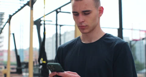 Close up of man using smartphone checking fitness applications standing at sport Stock Footage 246367431
