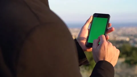 Close-up of man using smartphone with green screen against skyline Stock Footage 133375883