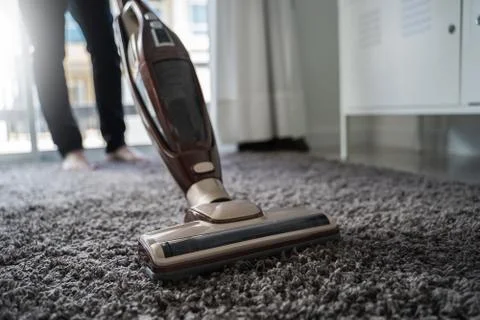 Close-up  man using a vacuum cleaner while cleaning in the room Stock Photos