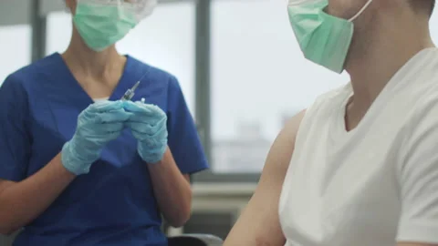 Close-up of a man vaccinating against coronavirus in a clinic, a medic makes an Stock Footage 150333385
