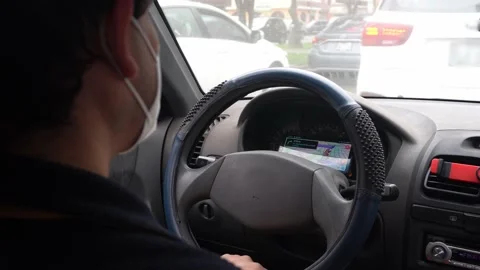 Close-up of a man waiting in traffic inside his car wearing a face mask for Stock Footage 156309698