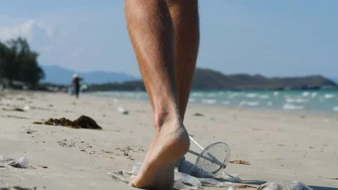 Close up of a man walking at the beach stepping on the plastics on the sand. Stock Footage 139326408