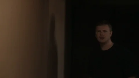 Close up of a man walking cautiously down a hallway. Stock Footage 99604736